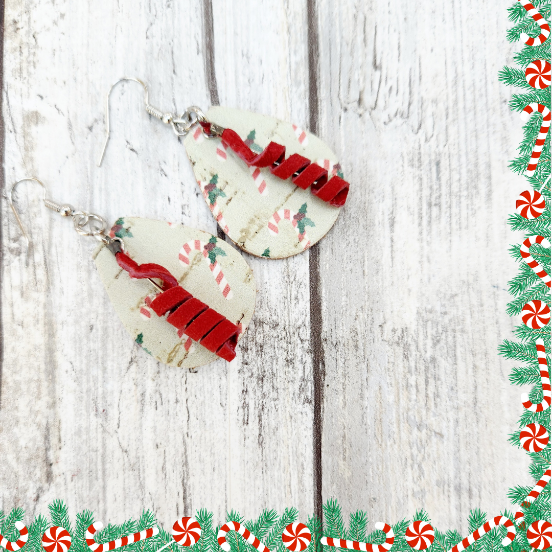 Christmas earrings on white wood wigh a fesrive border. Mint green cork on leather with a cute candy cane print, fronted by cheery red leather coils. 